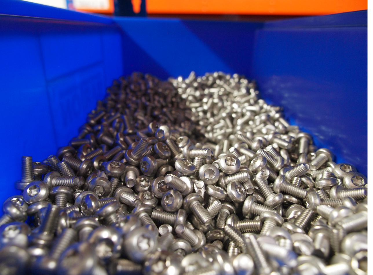 Pile of stainless steel button head Torx screws in blue bin