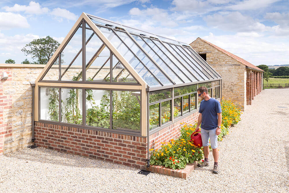 a glass greenhouse with a man watering plants